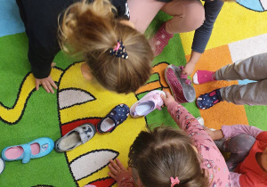 Dzieci dokładają swoje buty.